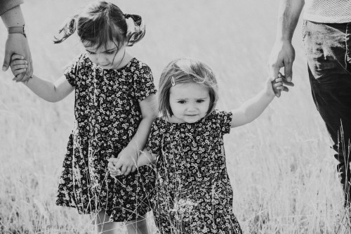 Zwei kleine Mädchen halten Händchen miteinander.