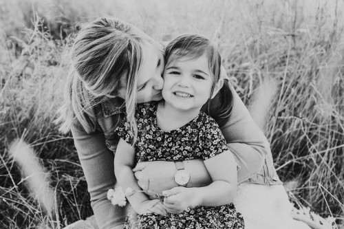 Ein kleines Mädchen und eine Frau sitzen auf einer Wiese.