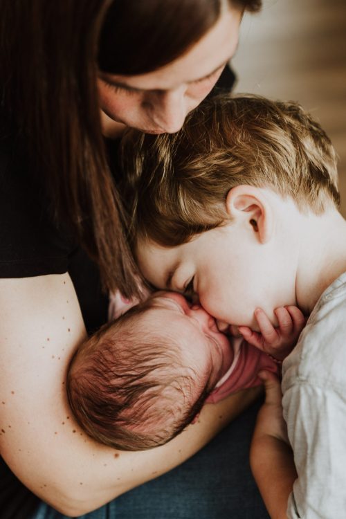 Ein kleiner Junge gibt einem Baby ein Küsschen.