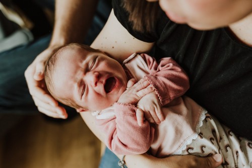 Ein kleines Baby schreit bei einer Frau auf dem Arm.