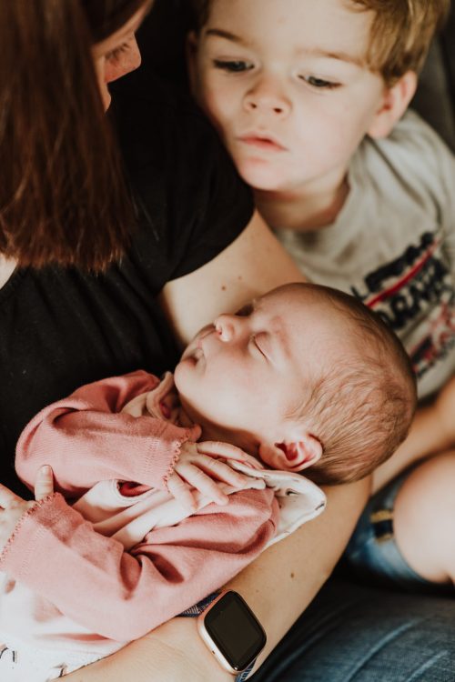 Ein kleiner Junge sieht ein kleines Baby an.