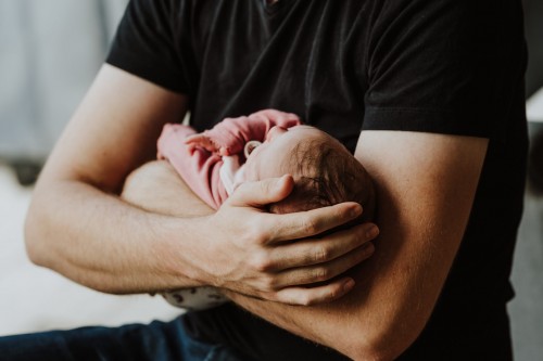 Ein Mann hält ein kleines Baby im Arm.