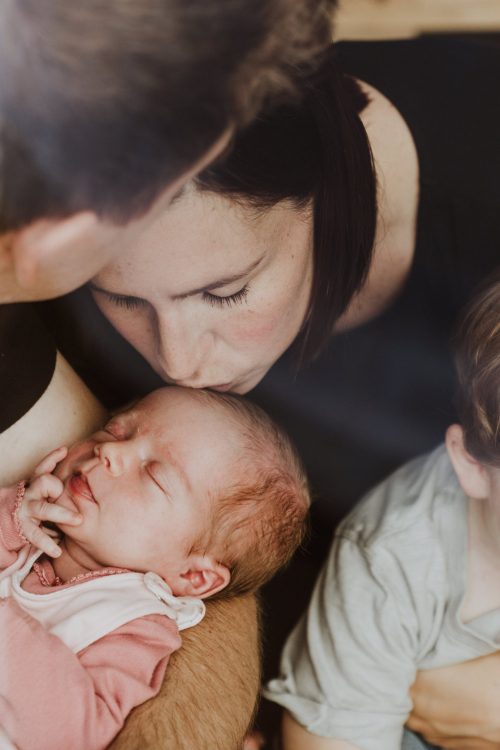 Eine Frau gibt einem Baby einen Kuss auf die Stirn.
