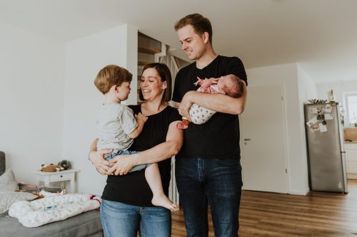 Ein Mann und ein Frau halten einen kleinen Jungen und ein neugeborenes Baby auf dem Arm.