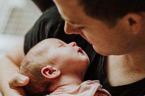 Ein Mann hält ein kleines schlafendes Baby auf dem Arm.