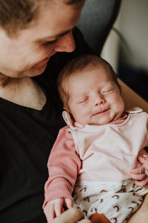 Ein Mann hält ein kleines Baby auf dem Arm.