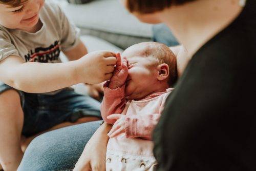 Ein kleiner Junge hält die Hand vom Baby.