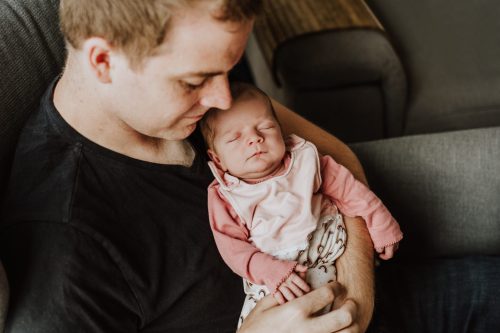 Ein Mann hält ein kleines Baby im Arm.