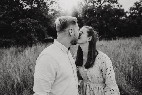 Eine Frau und ein Mann küssen sich auf einer Wiese.