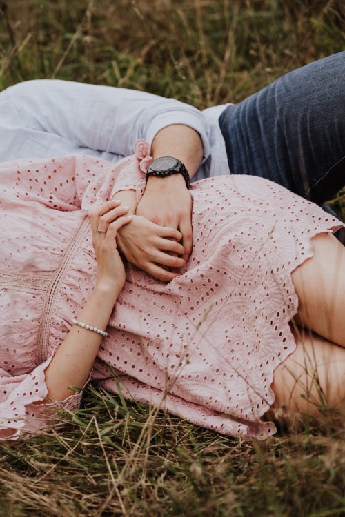 Eine Frau und ein Mann kuscheln auf einer Wiese.