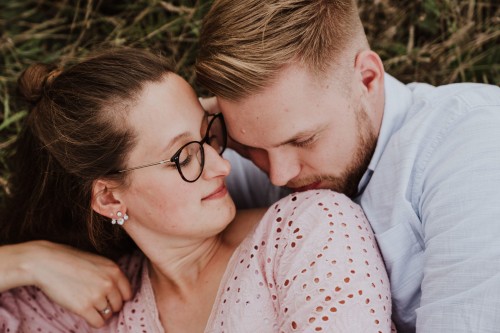 Eine Frau und ein Mann kuscheln auf einer Wiese.