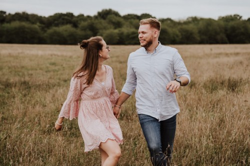 Eine Frau und ein Mann laufen durch eine Wiese.