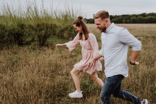 Eine Frau und ein Mann laufen durch eine Wiese.