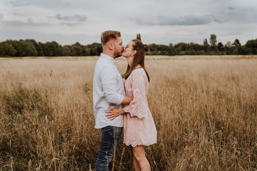 Ein Mann und eine Frau küssen sich mitten auf einer Wiese.