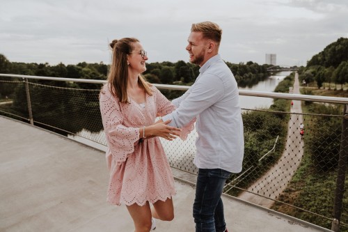 Eine Frau und ein Mann kuscheln auf einer Brücke.