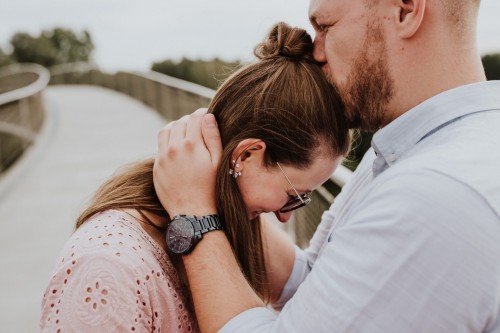 Ein Mann gibt einer Frau einen Kuss auf ihren Kopf.