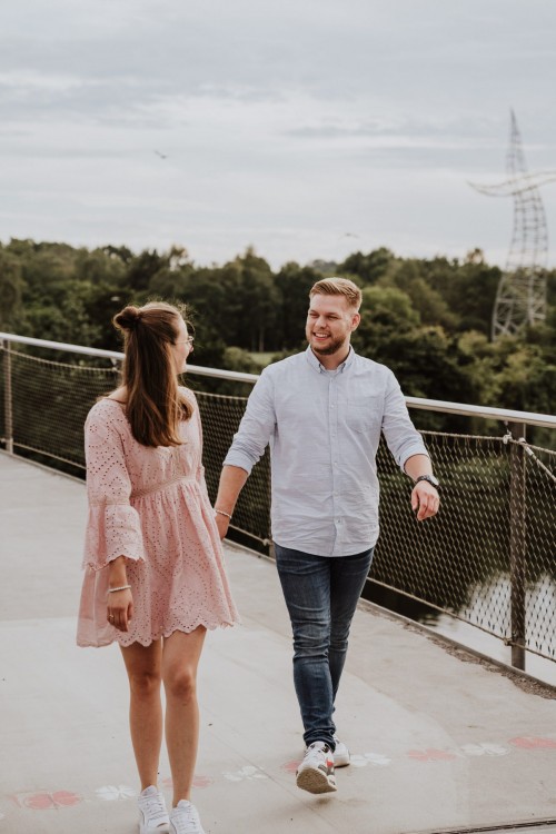 Eine Frau und Mann gehen händchenhaltend durch eine Brücke.