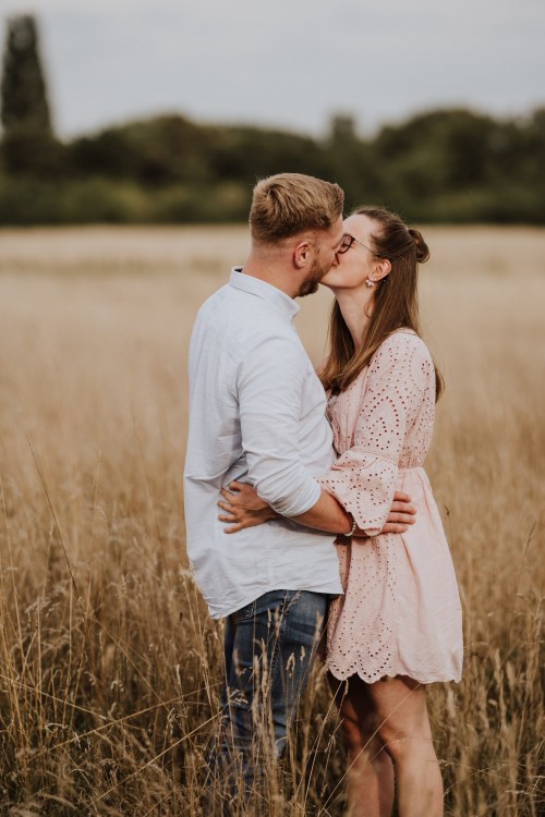 Eine Frau und ein Mann küssen sich auf einer Wiese.