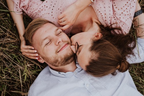 Eine Frau und ein Mann liegen auf einer Wiese und kuscheln.