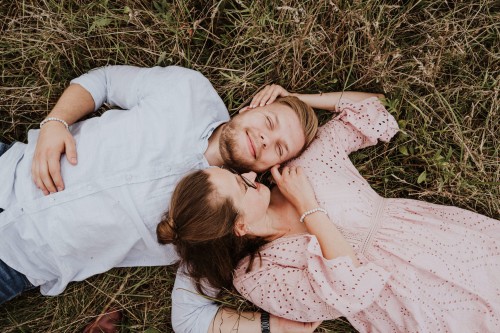 Eine Frau und ein Mann kuscheln auf einer Wiese.