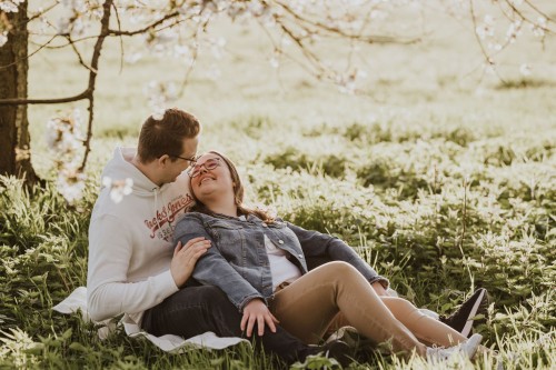 Eine Frau und ein Mann sitzen auf einer Wiese und kuscheln.