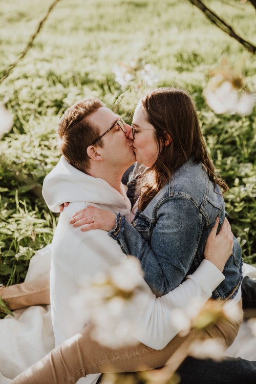 Eine Frau und ein Mann sitzen auf einer Wiese und küssen sich.