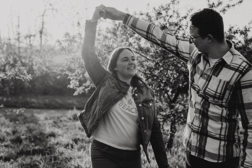 Eine Frau und ein Mann tanzen auf einer Obstwiese.