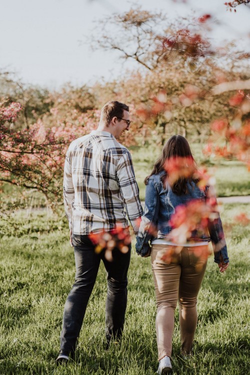 Ein Mann und eine Frau spazieren auf einer Obstwiese.
