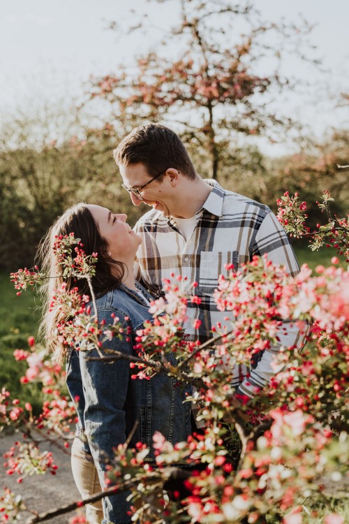 Eine Frau und ein Mann umarmen sich hinter einem blühendem Baum.
