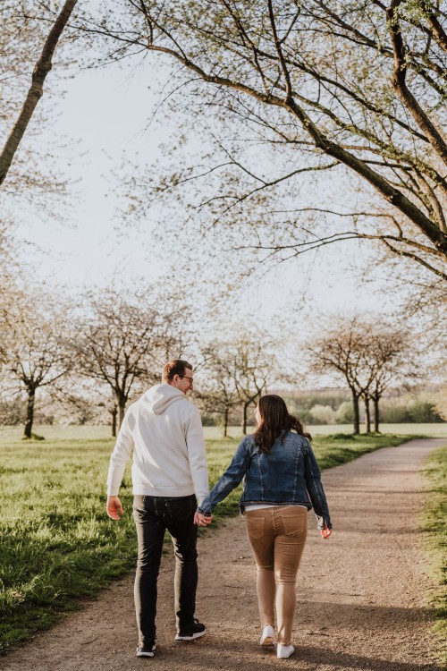 Eine Frau und ein Mann gehen einen Waldweg entlang.