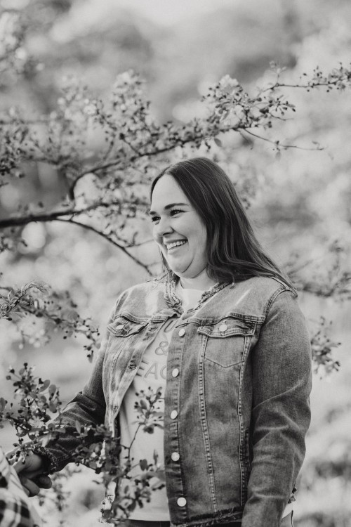 Eine Frau steht vor einem blühenden Obstbaum.