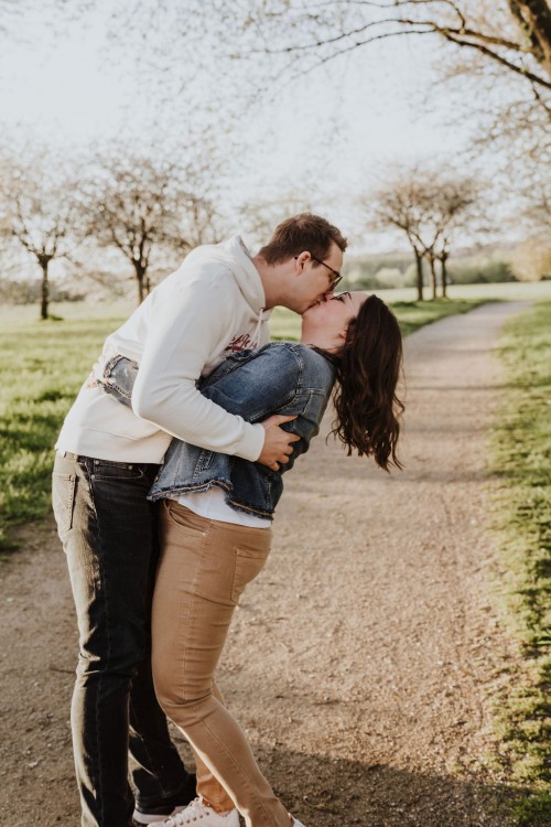 Ein Mann und eine Frau küssen sich auf einem Feldweg.