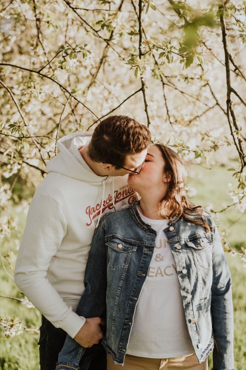 Ein Mann und eine Frau küssen sich vor einem Obstbaum.