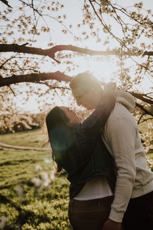 Eine Frau und ein Mann umarmen sich vor einem Obstbaum.