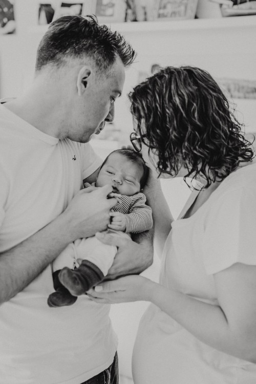 Eine Frau und ein Mann halten ein kleines Baby.