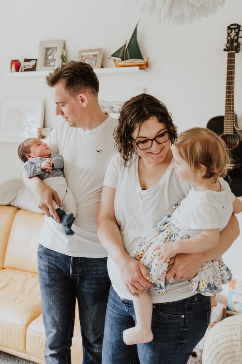 Ein Mann und eine Frau halten zwei kleine Kinder auf dem Arm.