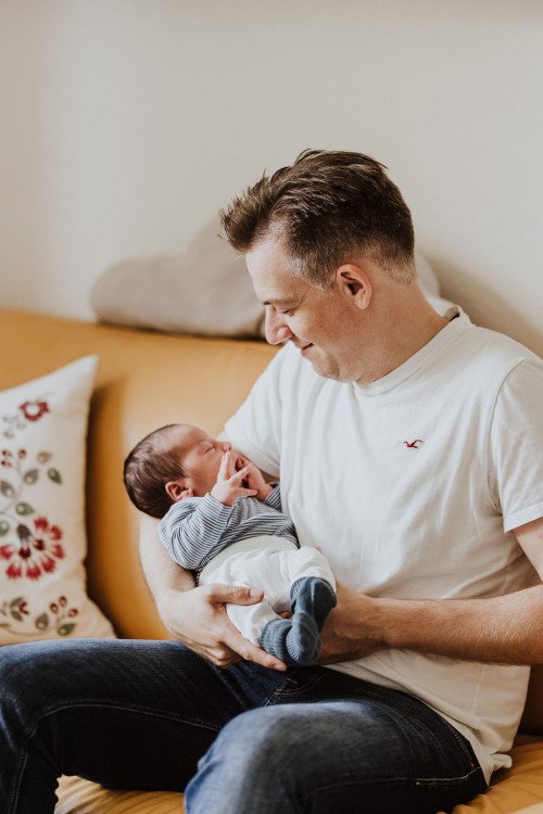 Ein Mann hält ein kleines Baby auf dem Arm.