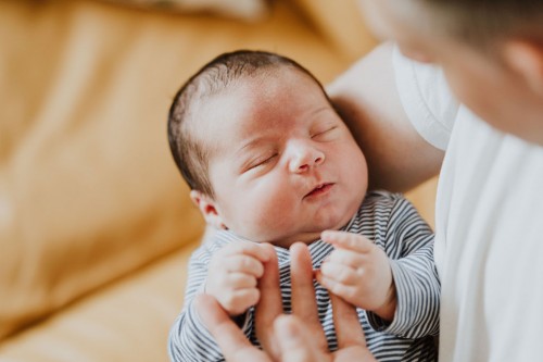 Ein kleines Baby auf dem Arm eines Mannes.