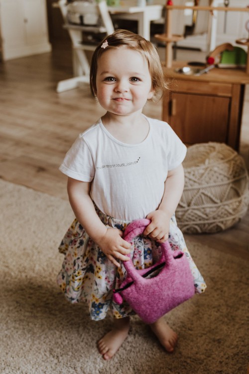 Ein kleines Mädchen mit einer pinken Handtasche.