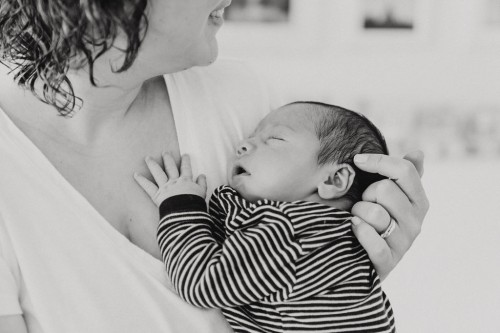 Ein kleines Baby schläft auf dem Arm einer Frau.