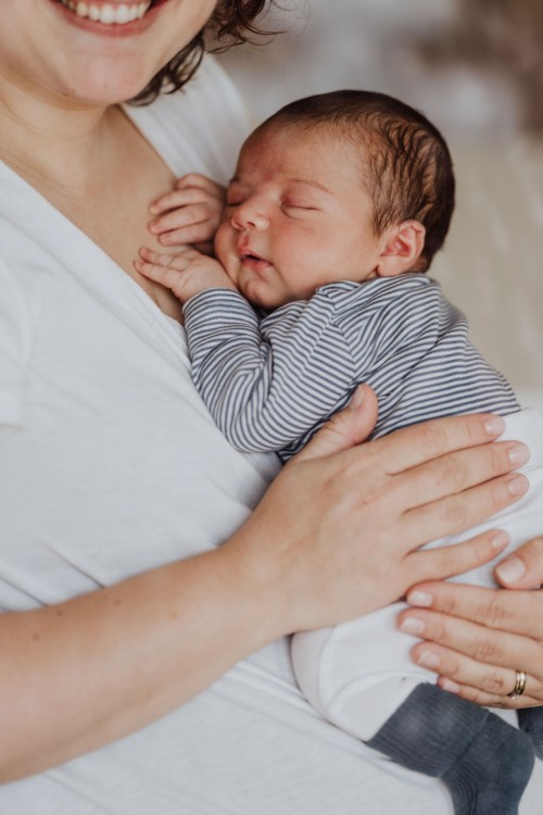 Ein kleines Baby liegt bei einer Frau an der Brust.