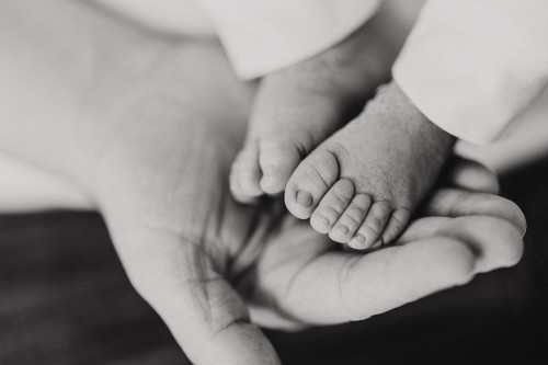 Kleine Babyfüße gehalten durch eine große Hand.