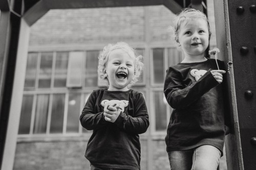 Ein Kind lacht sehr herzlich und das andere hält die Blume in der Hand und schaut nachdenklich