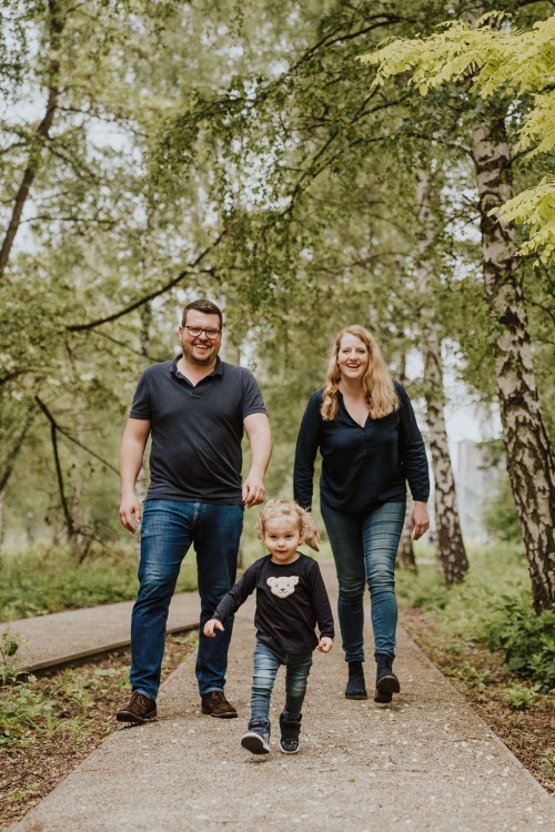 Ein kleines Mädchen und ihre Eltern spazieren durch die Grünfläche auf dem Gelände von der Zeche Zollverein