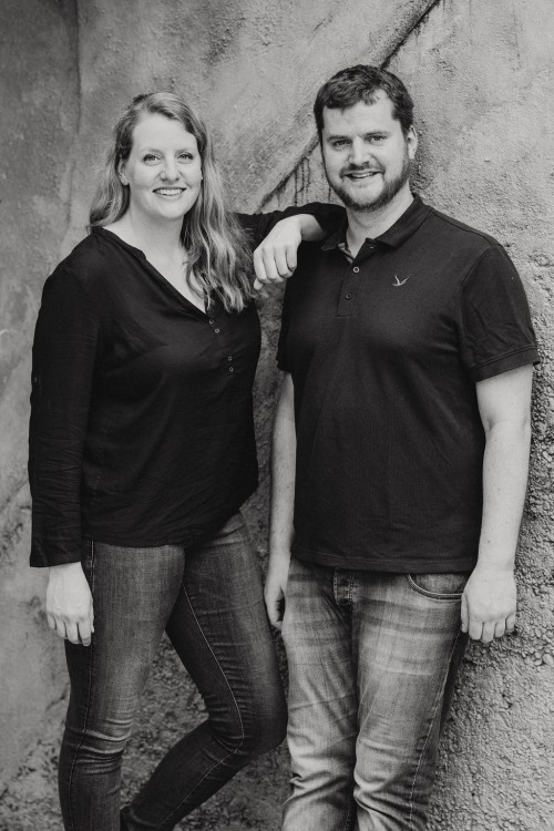 Posierte Aufnahme von einem Pärchen das lächelnd in die Kamera schaut