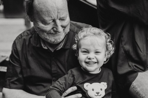 Der stolze Opa hält seine gut gelaunte Enkelin auf dem Schoss