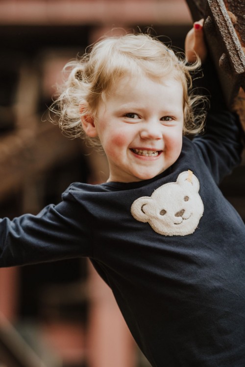Ein kleines Mädchen mit einem Teddybär auf ihrem Oberteil