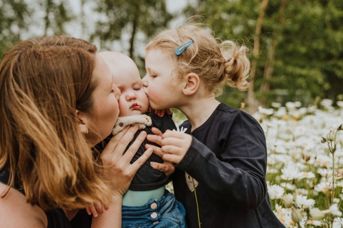 Ein Baby bekommt von links und rechts einen dicken Kuss.