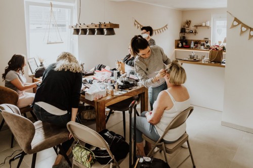 Eine Gruppe von Frauen sitzen am Tisch und werden geschminkt.