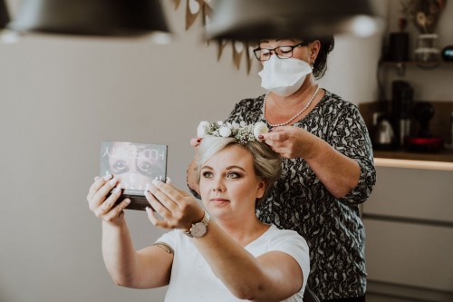 Einer Frau wird ein Blumenkranz auf den Kopf gelegt.
